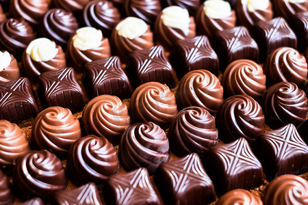 米色摄影照片_什锦的白、 牛奶和黑巧克力糖果背景，选择性焦点
