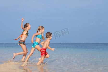 沙滩上的孩子摄影照片_三个快乐的孩子们在沙滩上玩