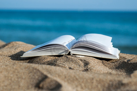 书籍摄影照片_在海滩上打开的书籍特写