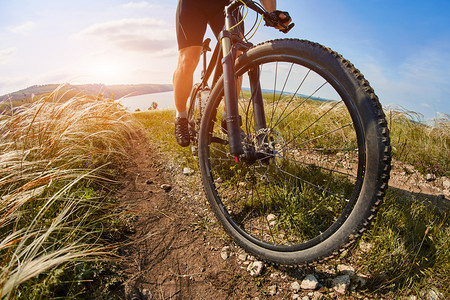 骑单车骑山地自行车穿过绿色的草地，对美丽的天空.