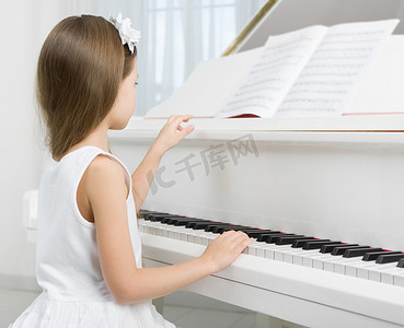欧美教育摄影照片_小女孩在弹钢琴的白色连衣裙的侧视图