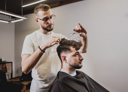 在理发店理发的年轻人. 理发师负责理发和修剪胡子. 概念理发店.