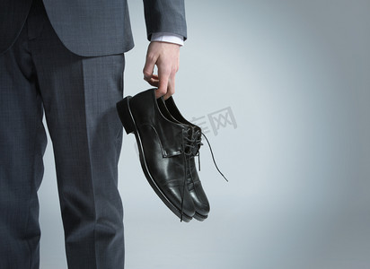 close摄影照片_Businessman holding the shoes in hand, close up