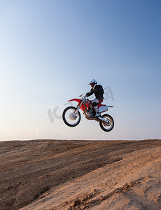 摩托车摄影照片_骑手表演绝技在沙漠里