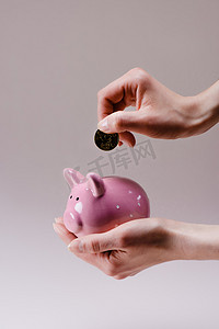 裁剪拍摄的妇女投入50欧元到粉红色的小猪银行手上孤立的丁香花