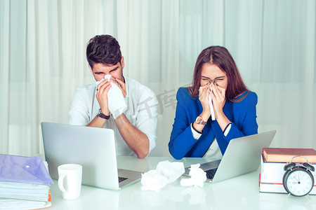 在家里的办公室客厅里, 年轻男女夫妇同事们一起坐在餐桌旁, 擤鼻涕。流感病毒 allergia, 流感从空调概念.