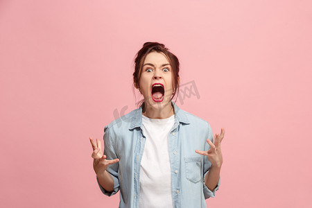 校长表情摄影照片_年轻的情绪愤怒的女人尖叫粉红色工作室背景