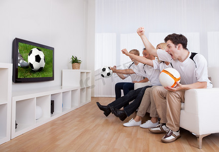 电视足球摄影照片_欢腾的家人看电视