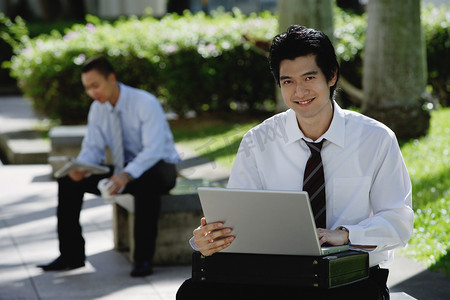多人在公园里使用笔记本电脑的面带微笑的商业职场成功男士 