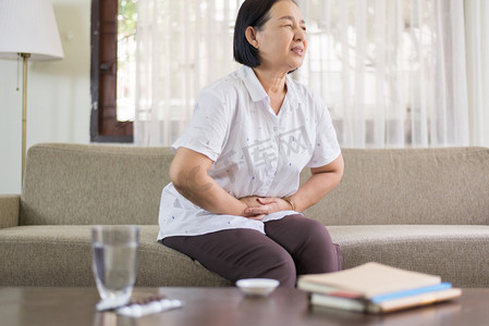 年长亚洲妇女在家中疼痛，老年女性患腹痛
