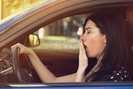 睡眼惺忪的打呵欠女子驾驶她的车经过长时间的旅行. 