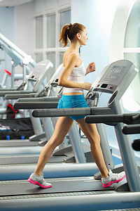 美女动感摄影照片_正在跑步机上进行有氧运动的美女