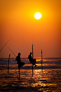 著名的地方摄影照片_传统的高跷渔民在日落 nea 的剪影