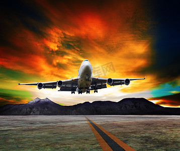 喷气式客机摄影照片_喷气式飞机飞越跑道对岩石山和美丽的昏暗天空与航空运输、 旅行和旅游行业复制空间的使用