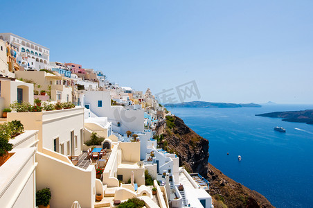 Panorama of Fira with whitewashed buildings carved into the rock on the edge of the caldera cliff on the island of Thira (Santorini), Greece.