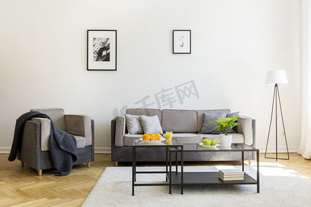 开业海报海报设计摄影照片_沙发前地毯上的黑色桌子和客厅内有海报的扶手椅。真实照片
