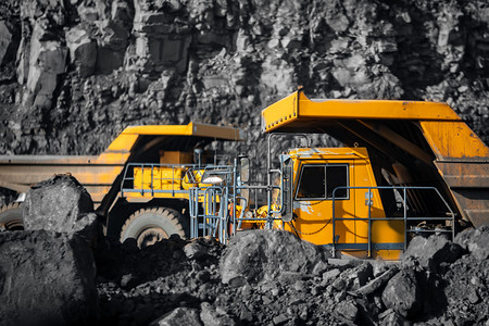挖掘机摄影照片_大型黄色矿用卡车载满无烟煤移动露天煤矿