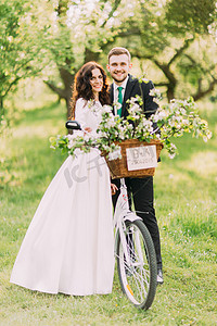 对的人摄影照片_愉快的新婚夫妇在婚礼后在公园里用自行车摆姿势