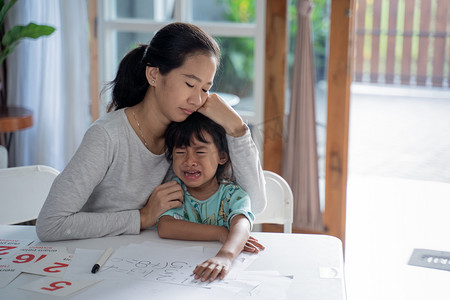 亚洲孩子摄影照片_母亲安慰着她在家里哭泣的母亲
