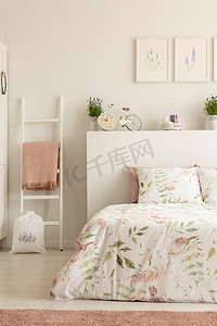 粉红色摄影照片_真正相片白色卧室内部与自行车形状的时钟, 肮脏的粉红色毯子在梯子和花床单在床上
