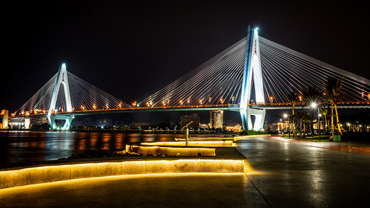 海口市海口地标海岸线沿线的世纪大桥夜景秀丽，长廊灯火通明（翻译：世纪大桥 )