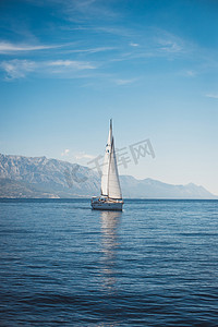 帆船海洋摄影照片_在高山背景下的海面上航行的游艇