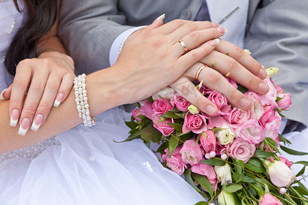新郎和新娘在婚礼的花束上的手