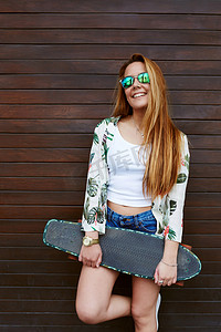 欧美服装背景摄影照片_十几岁的女孩，抱着滑板的太阳镜