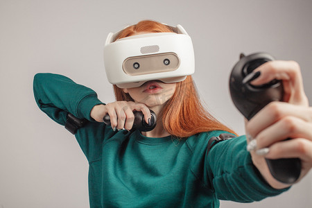灰色科技摄影照片_自信的红头发的女人戴着虚拟现实耳机, 瞄准弓