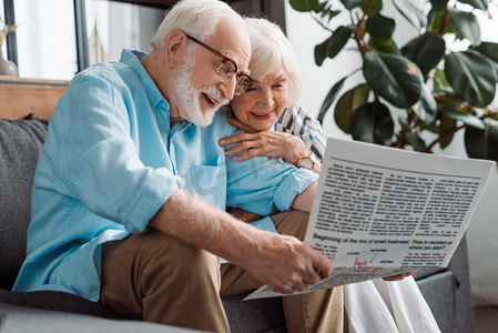在客厅沙发上看报纸的老夫妇笑着