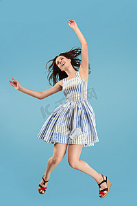 自由移动。漂亮的年轻女子跳对蓝色背景