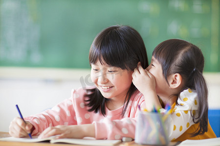 分享小学摄影照片_两个年轻女孩耳语和分享的秘密