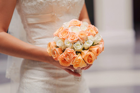 新娘紧握着白色和粉色的玫瑰的婚礼花束