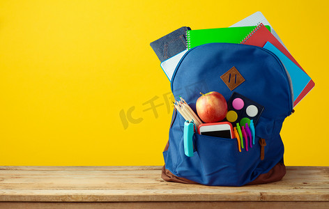 传奇大背包摄影照片_带笔记本、智能电话和铅笔的书包背包, 上面有黄色背景.