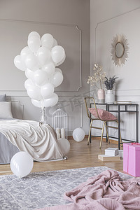时尚卧室设计的垂直视图, 配有一堆白色气球、带金色椅子和镜子的时尚梳妆台, 以及地板上的粉色材料