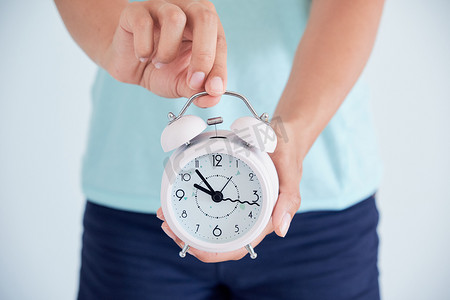 关闭一个生病的年轻妇女与时钟在她的手中。月经周期调节的概念。是时候照顾健康了