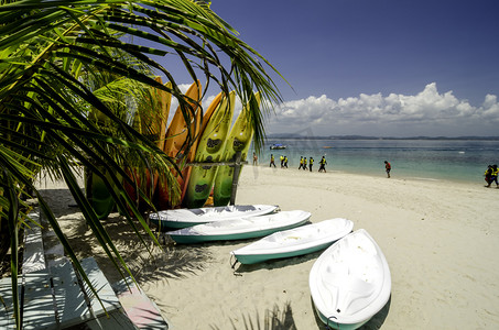 黄色照片摄影照片_在晴朗的日子, 在白色沙滩上五颜六色的堆叠独木舟。蓝天和清澈的海水背景. 马来西亚 Kapas 岛 (棉花岛) 拍摄的照片