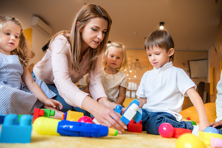 幼儿园牌子摄影照片_教育工作者帮助孩子们在幼儿园里玩建设者