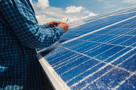 打光摄影照片_在太阳能发电厂更换太阳能电池板的工程师团队; 工程师和电工团队交换和安装太阳能电池板;电工小组检查破窗格上的热点