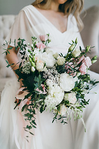 迷人新娘穿着白色连衣裙的手中的白色和粉红色的华丽花束。图稿
