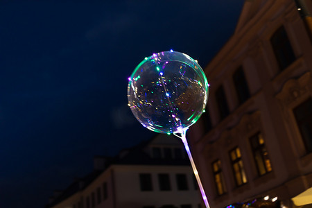 led背景灯光摄影照片_卢布林, 波兰-2018年7月27日: Led 透明气球与多色发光花环。夜晚的灯光很鲜艳。在卢布林街道上的照明气球