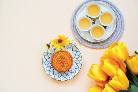 中国月饼的平躺在黄色背景, 节日和节日的概念的热茶和花