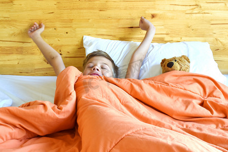 手绘多肉伸展摄影照片_这个男孩早上在床上醒来。 #清晨的双手伸展#.