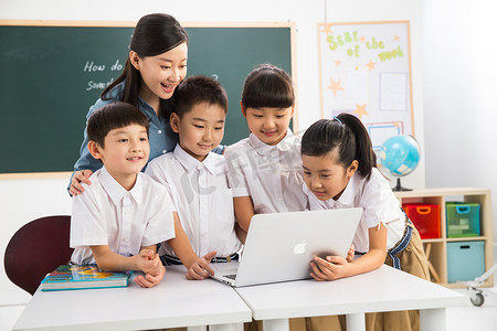 教师和小学生在教室里使用电脑