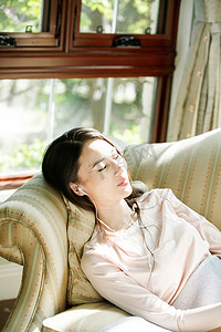 时尚音乐音乐摄影照片_青年女人躺在沙发上听音乐