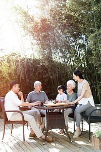 冒烟的茶杯摄影照片_幸福家庭在院子里喝茶