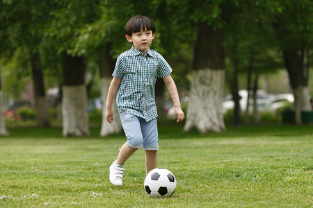 日光庭院摄影照片_小男孩踢足球