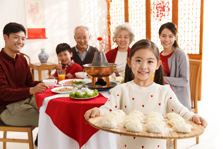 三代同堂摄影照片_小女孩过年端着饺子