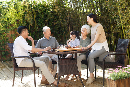日光庭院摄影照片_幸福家庭在院子里喝茶