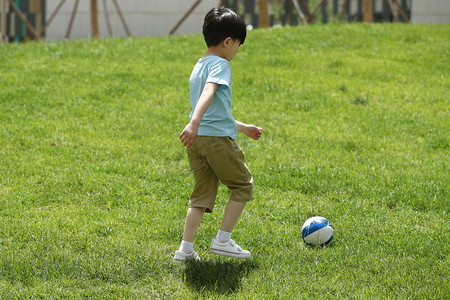 小男孩在草地上踢球